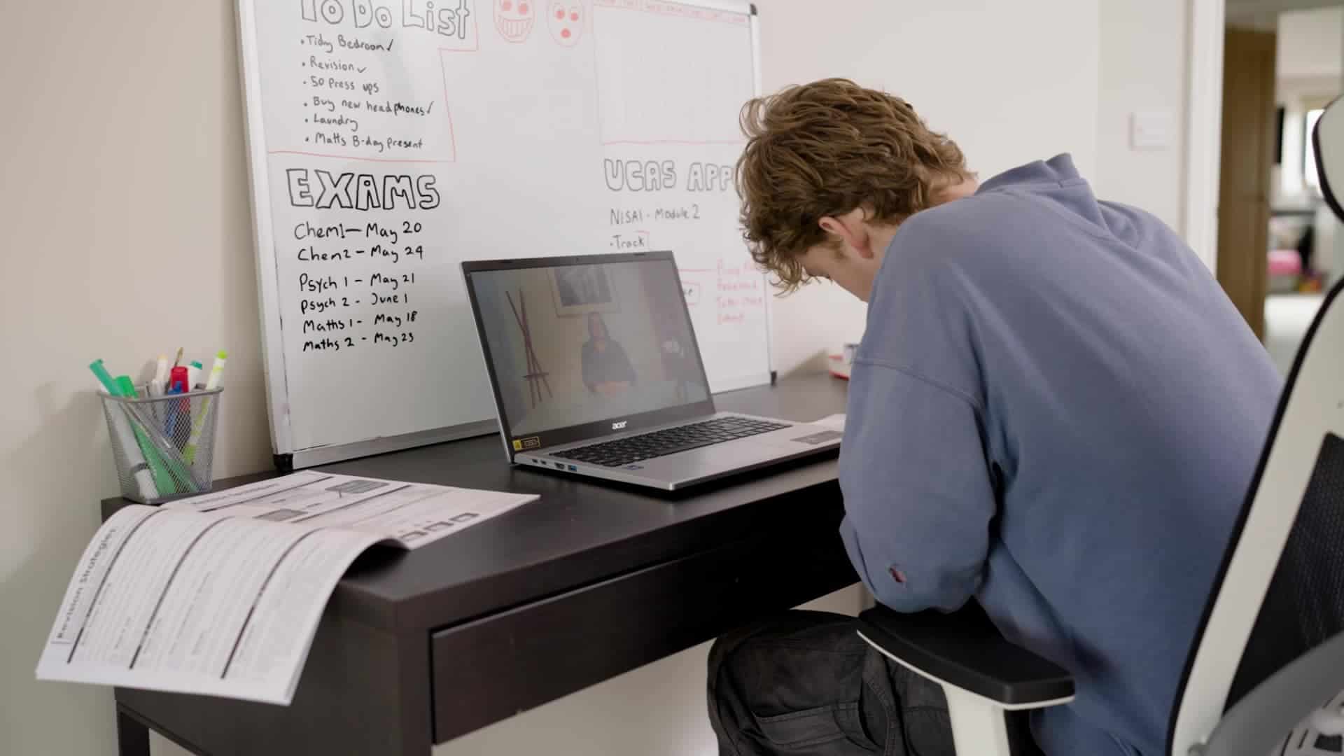 Student engaged in online learning at Nisai Learning with a laptop and whiteboard background.
