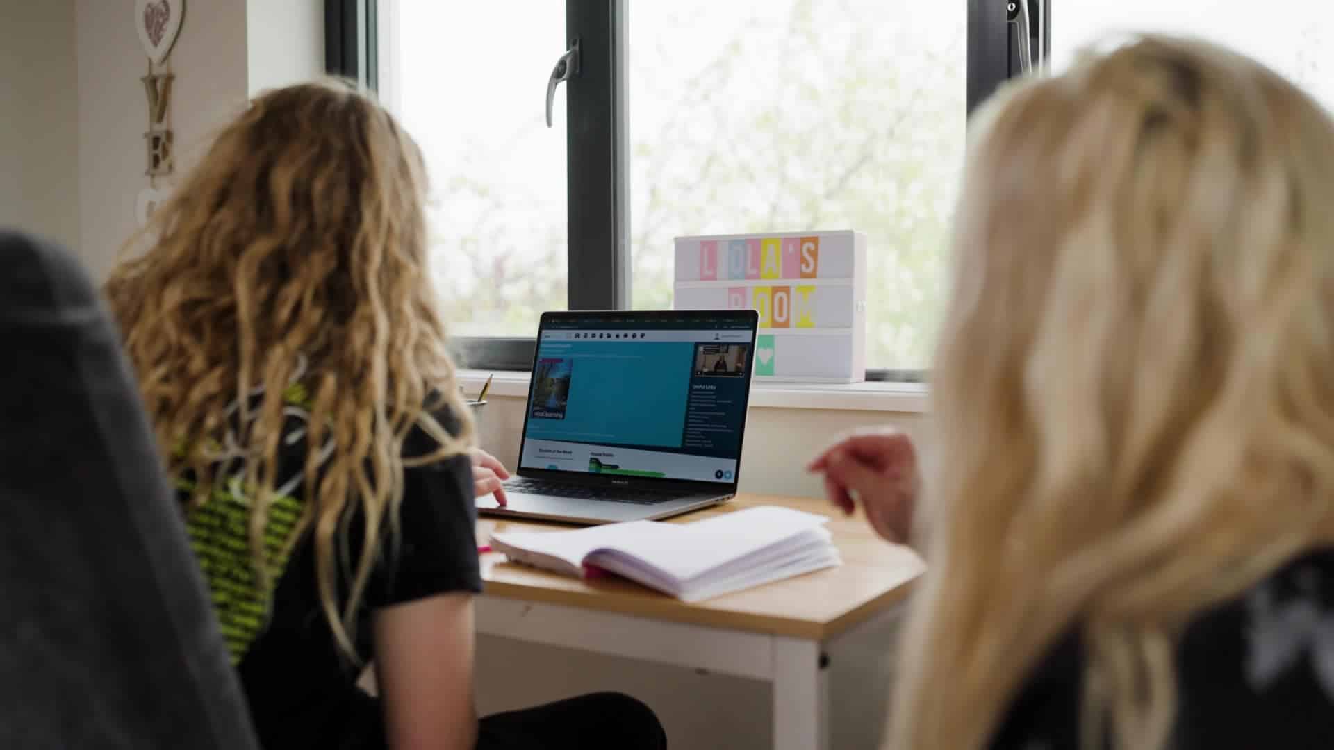 Students engaging in online learning at a computer in a classroom.
