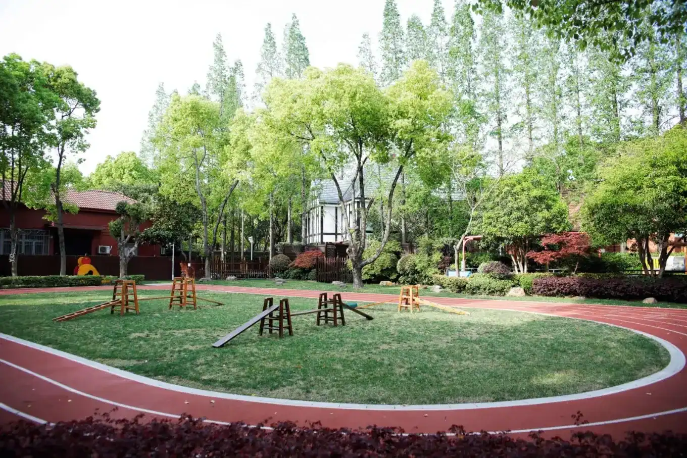 Playground at Dulwich College Shanghai Pudong with green trees and sports equipment.