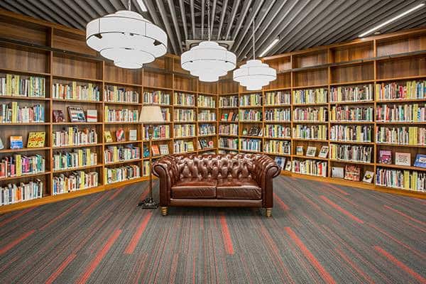 Library interior at Dulwich College Shanghai Pudong with bookshelves and comfortable seating.