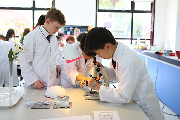 Students conducting science experiments in a modern classroom at Dulwich College Shanghai Pudong.