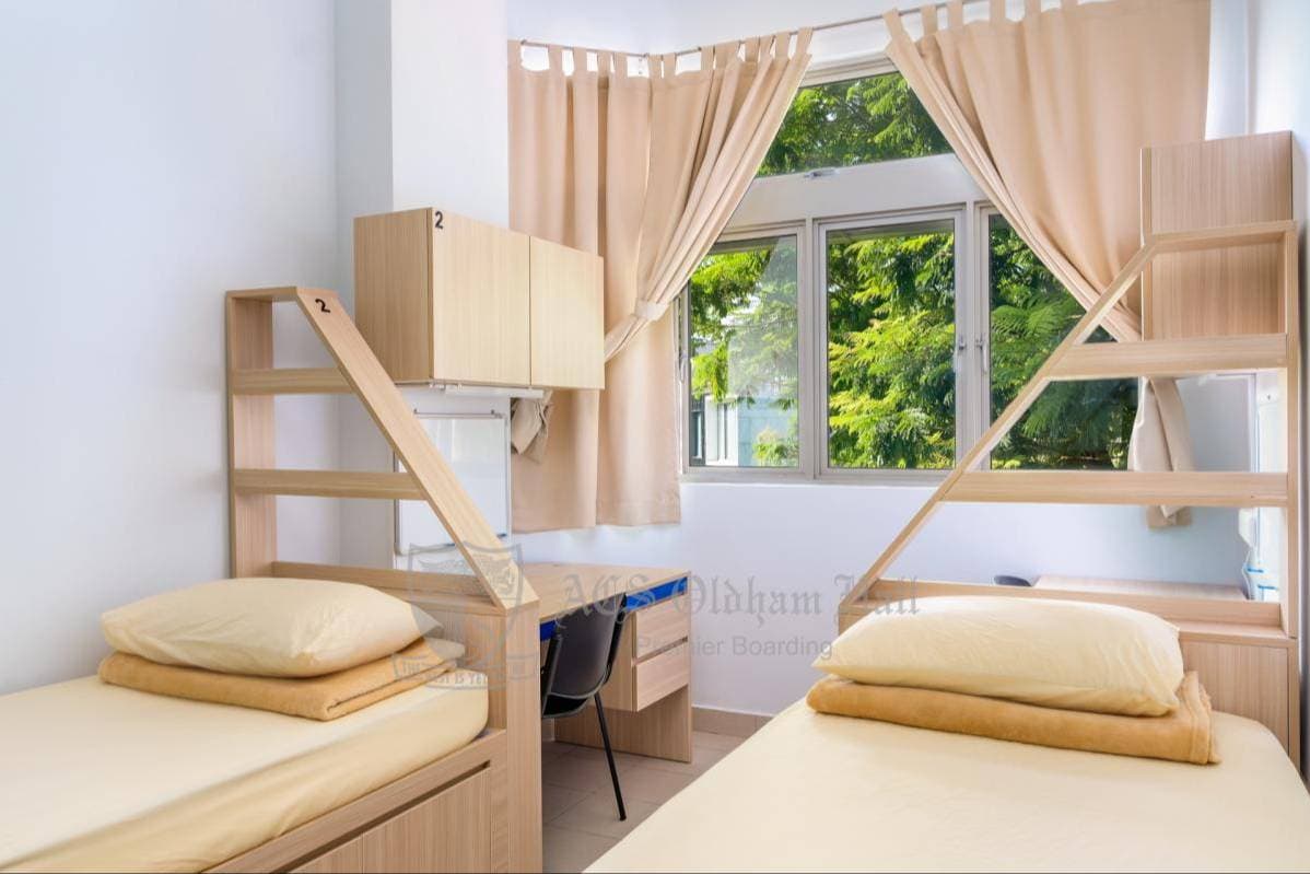 Comfortable twin beds with wooden furniture and a bright window overlooking greenery.