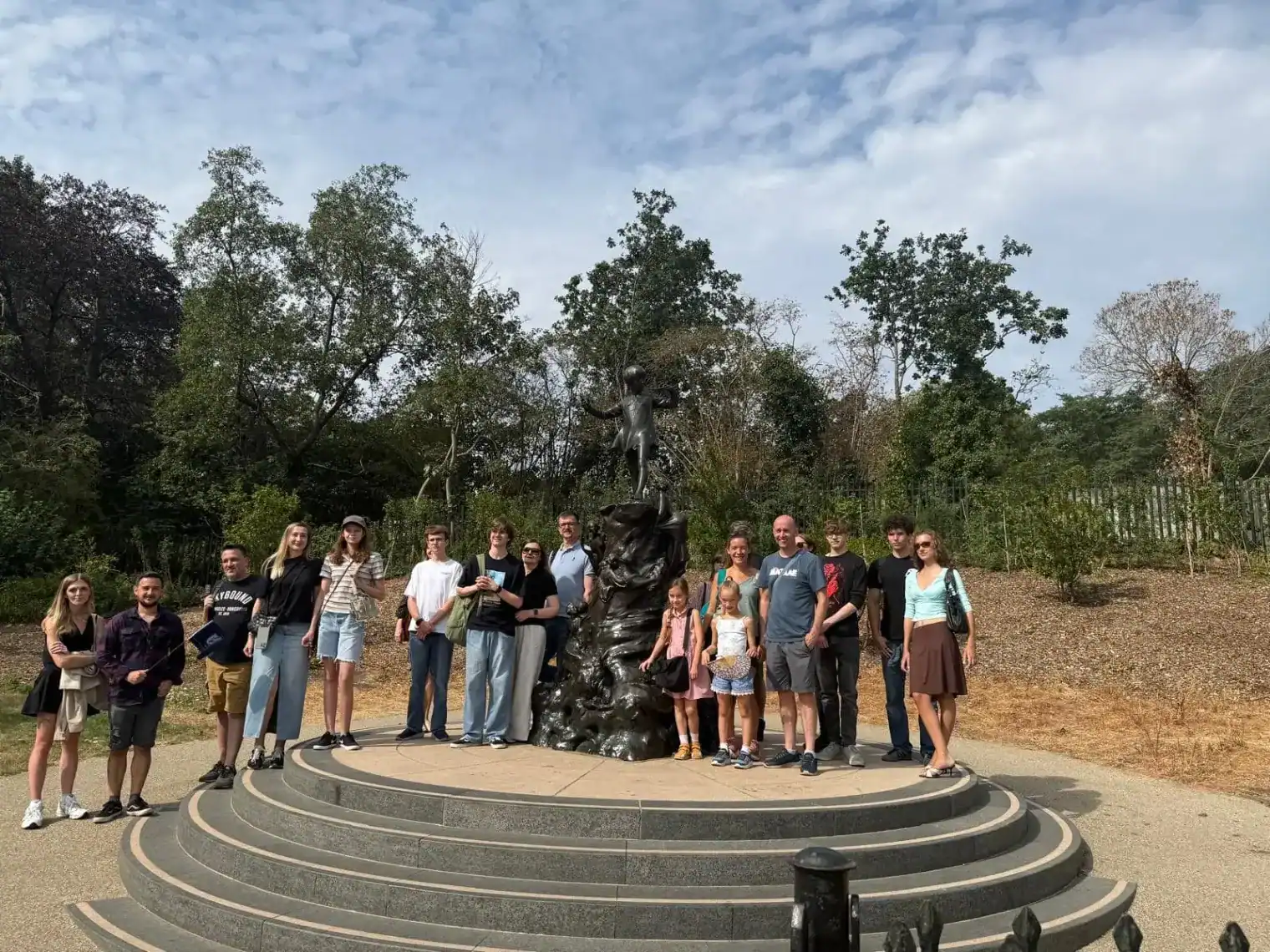 Group of students and teachers at a monument in a park setting.