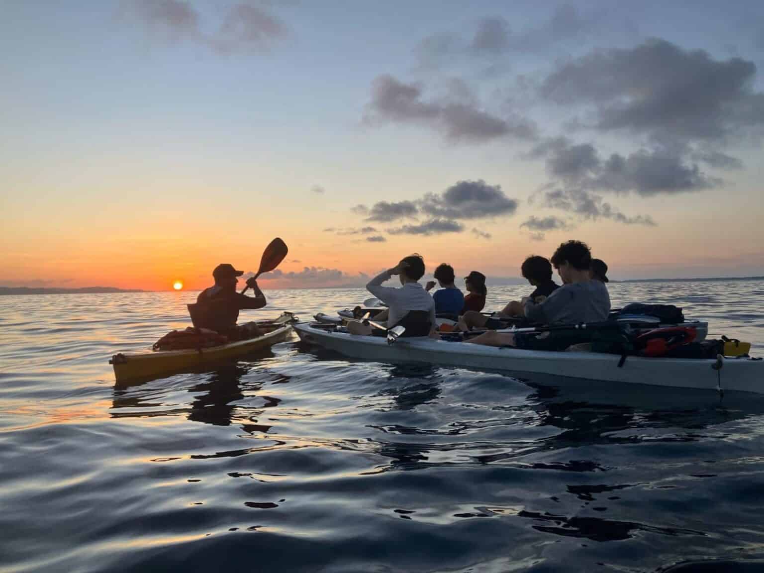 Students kayaking during sunset on calm waters at a school trip or outdoor adventure.