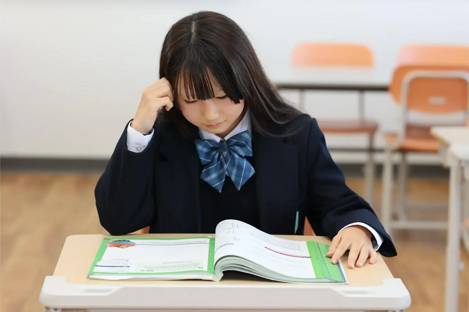 Focused Asian student studying in classroom, emphasizing world schools and academic excellence.