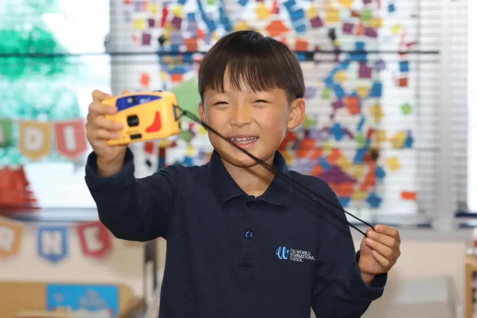 Young boy smiling with a tape measure, engaging in creative learning at World Schools.