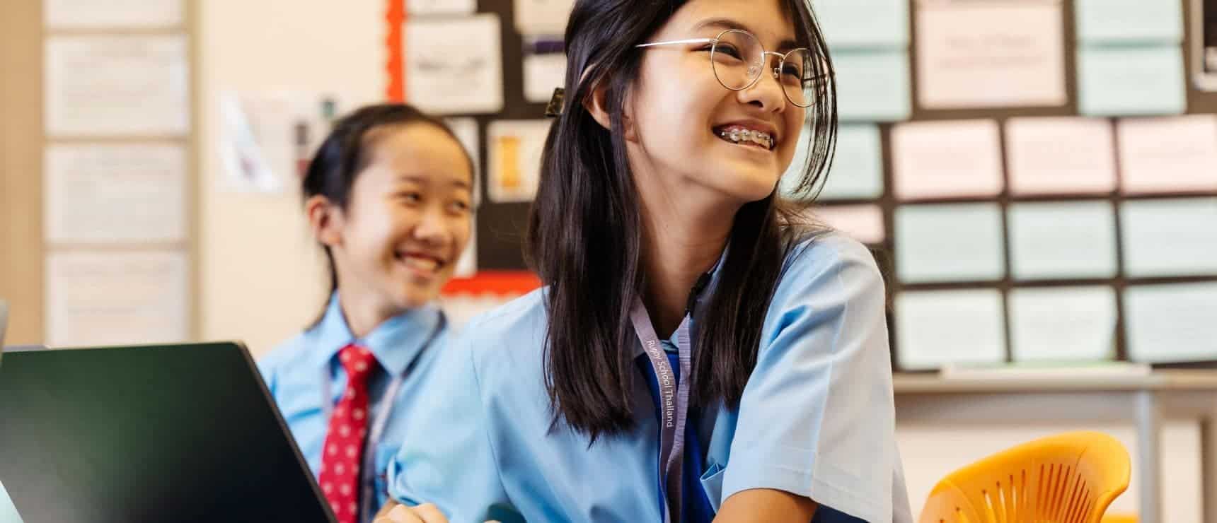 Bright Asian student smiling in classroom, promoting international school education and global student community.