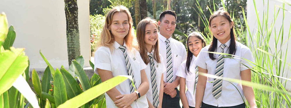 Elegant students in school uniforms standing outdoors among lush greenery, representing World Schools education.