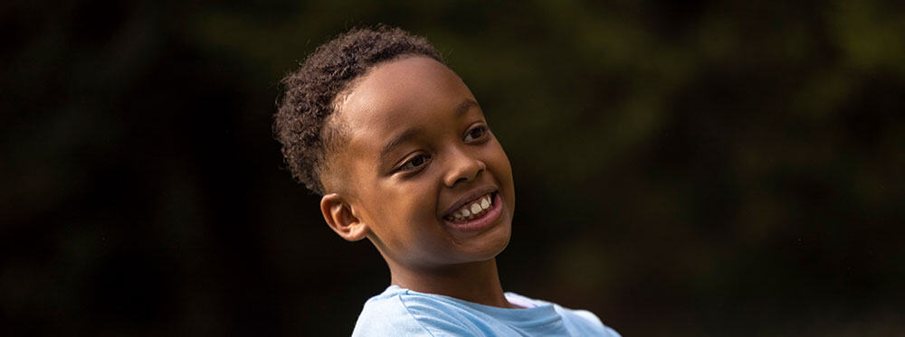 Bright smiling young boy enjoying outdoor activities at World Schools international education campus.