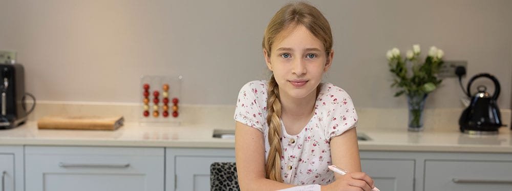 Bright young girl studying in modern kitchen, showcasing world school education and global learning opportunities.