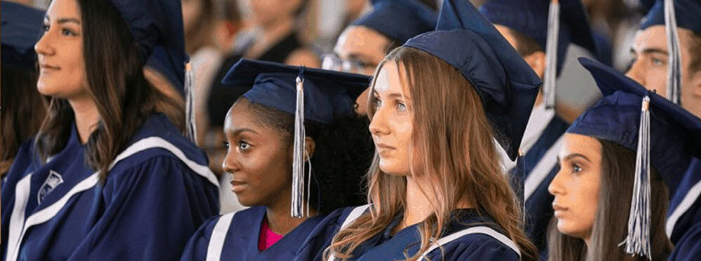 Graduates in blue caps and gowns attending a World Schools graduation ceremony.