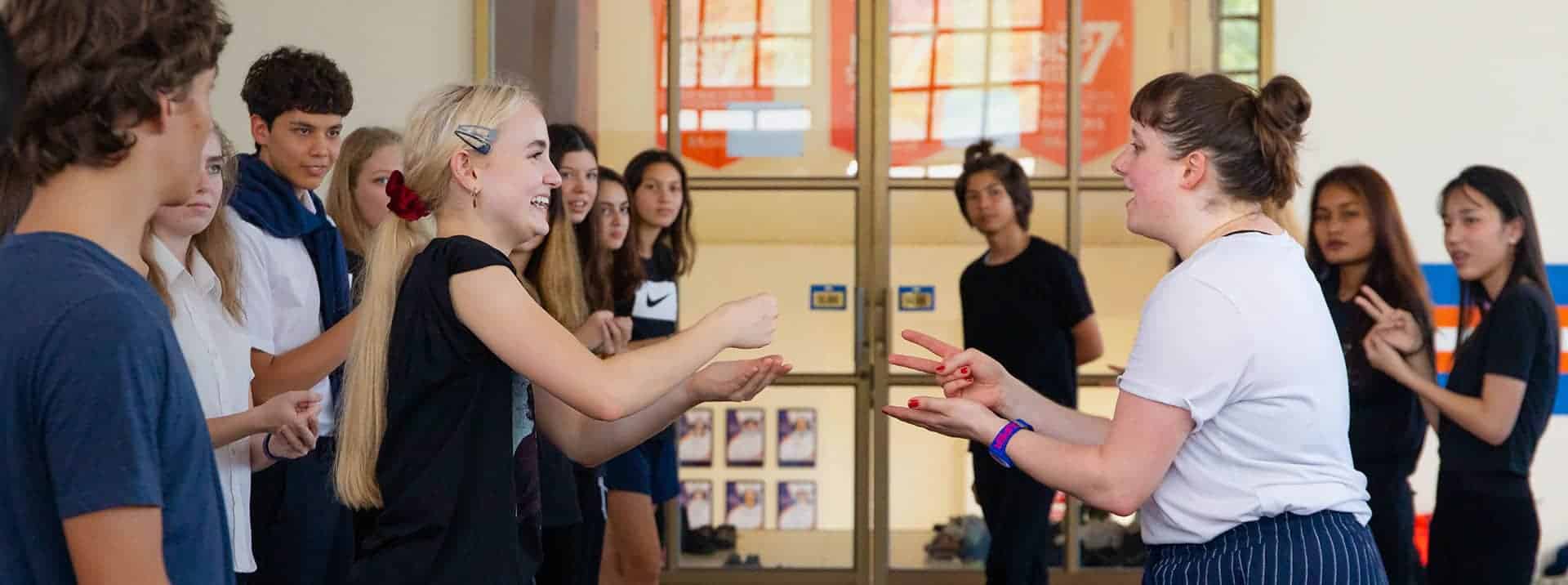 Bright diverse students engaging with teacher during lively classroom activity at a world school.
