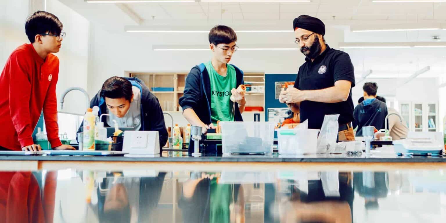 Wetenschappelijke docent begeleidt diverse leerlingen in een modern wetenschapslaboratorium.