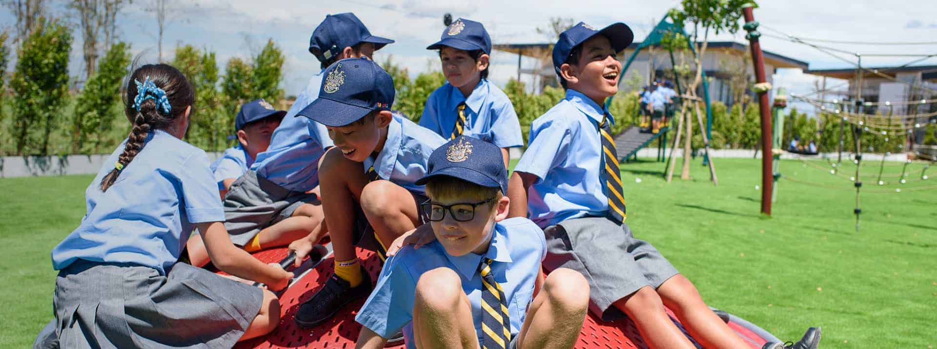 Children in school uniforms playing outdoors at a global school campus.