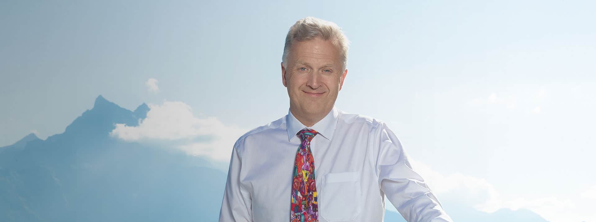 Experienced business professional in a sky background promoting global education on World Schools site.