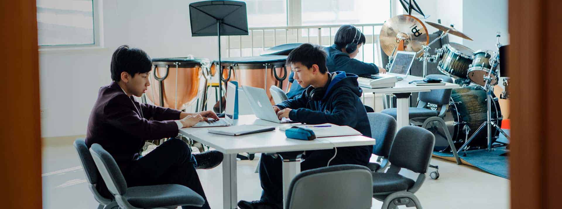 Students engaged in digital learning and music activities at a modern international school classroom.