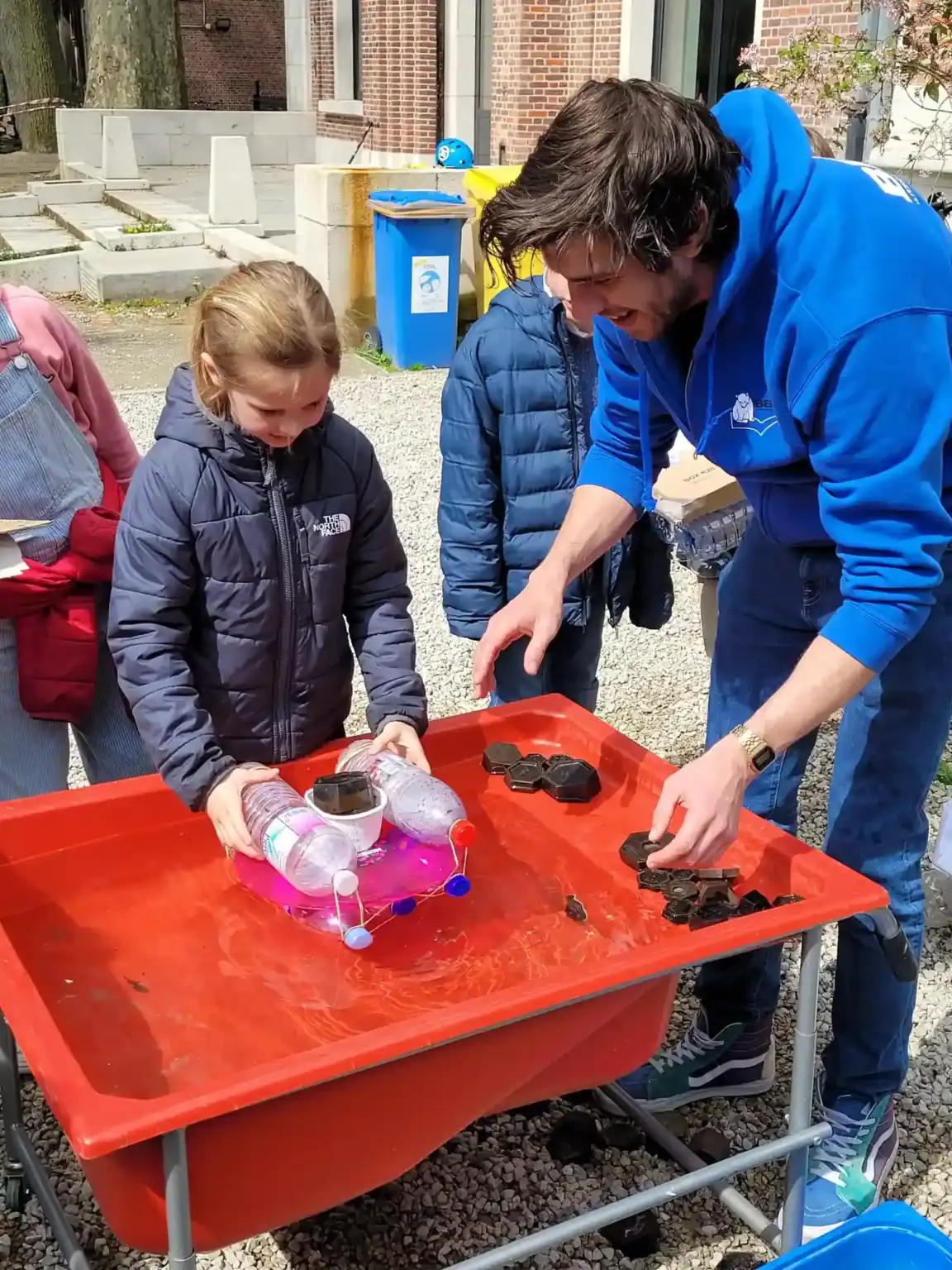 Colorful outdoor science activity with children and instructor at a school event.