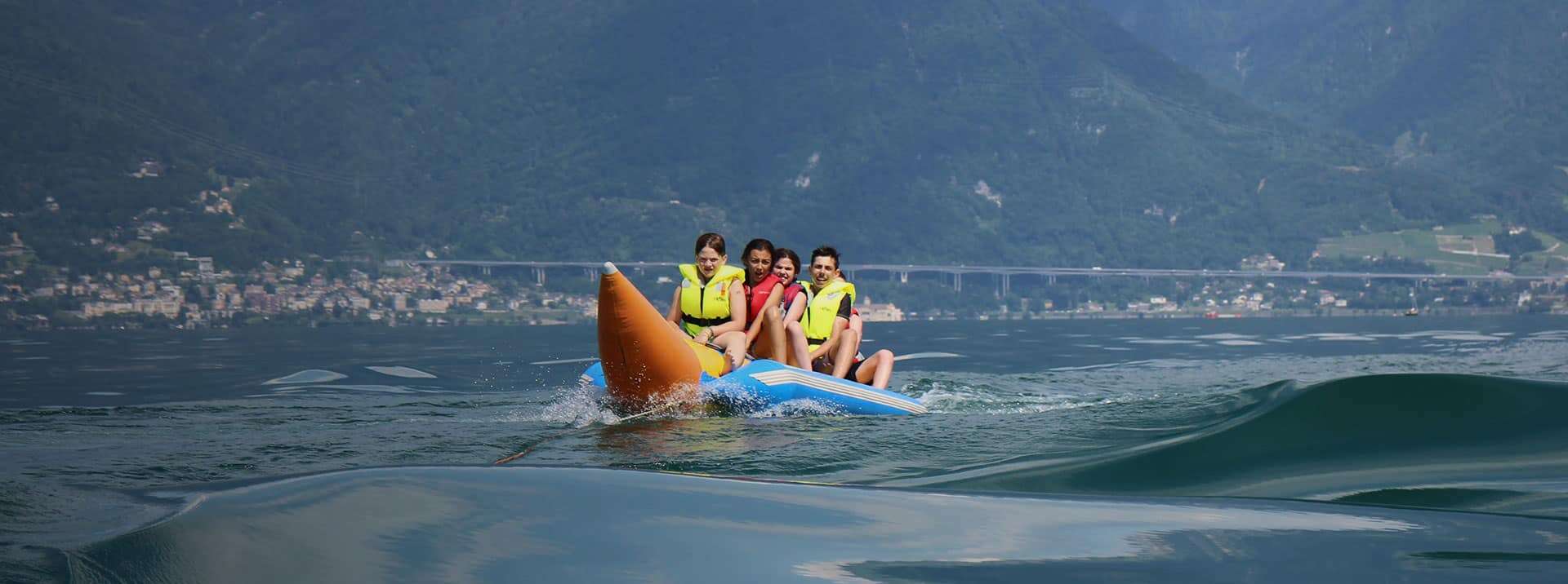 Excited kids on a kayak adventure, enjoying water sports with scenic mountain and lake views.