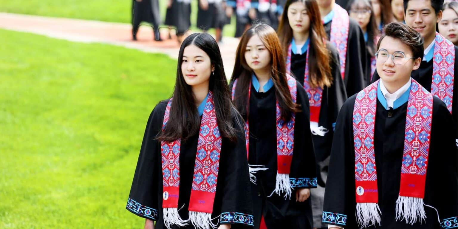 Studenten in toga's en traditionele sjerpen tijdens een internationale schoolceremonie.