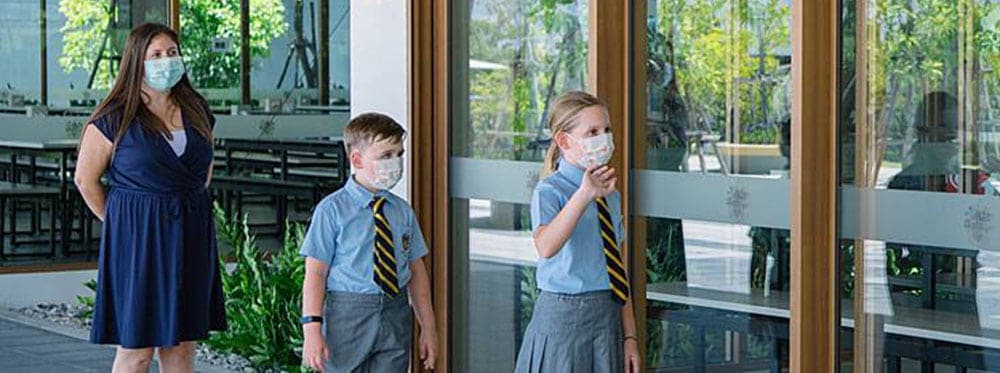 Children and teacher wearing masks at World Schools during open-air learning.