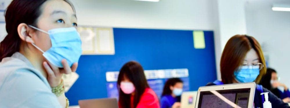Students wearing masks in a classroom at global schools or international schools.