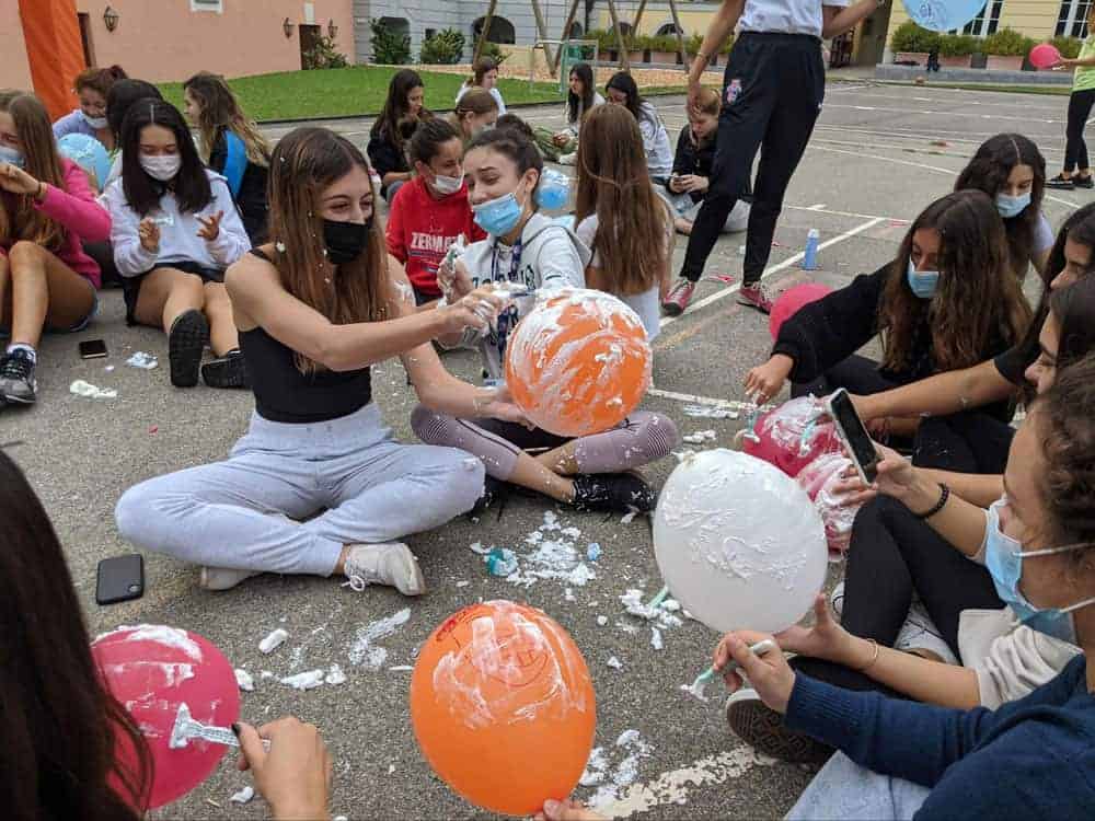 Colorful balloons being popped during outdoor school activity at World Schools event.