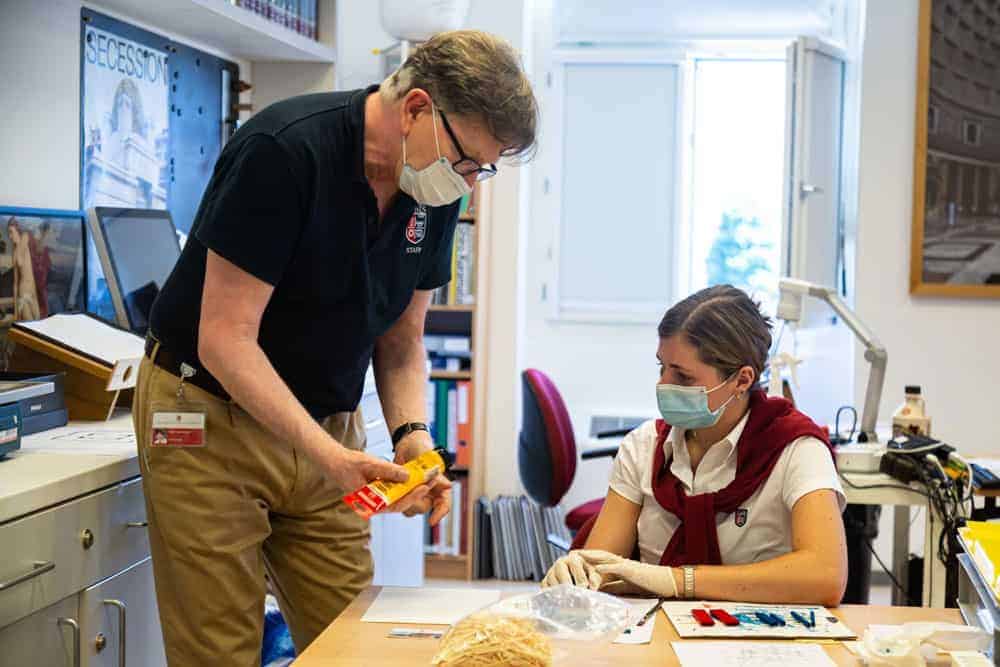 Adult male teacher and female student wearing masks working on a science project in classroom.