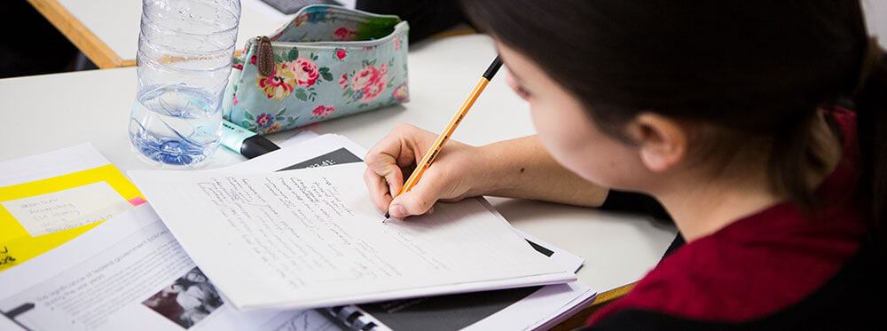 Focused student studying and taking notes at a desk, promoting academic excellence and world-class education.