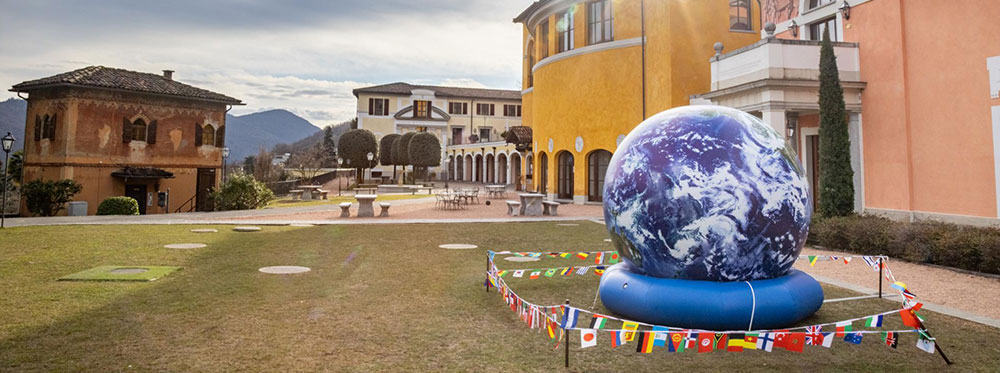 Earth globe sculpture at World Schools campus with colorful international flags, emphasizing global education excellence.