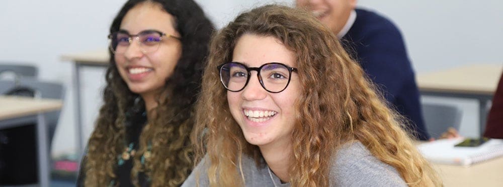 Diverse students smiling in classroom, promoting World Schools education and global learning excellence.