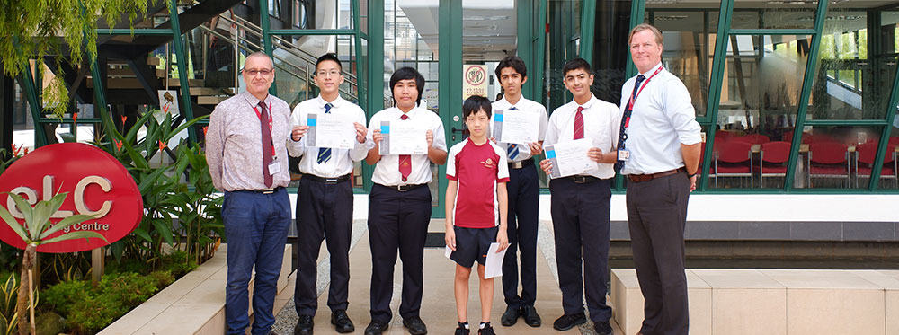 High-achieving students and teachers at an international school in front of a modern glass building.