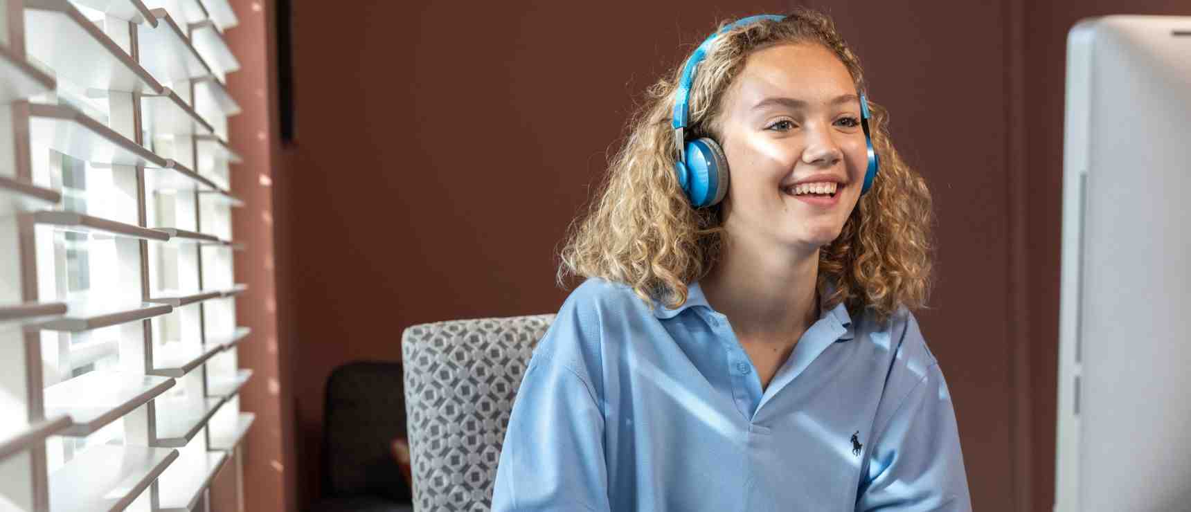 Bright student attending online school with headphones at home, promoting global education and virtual learning.