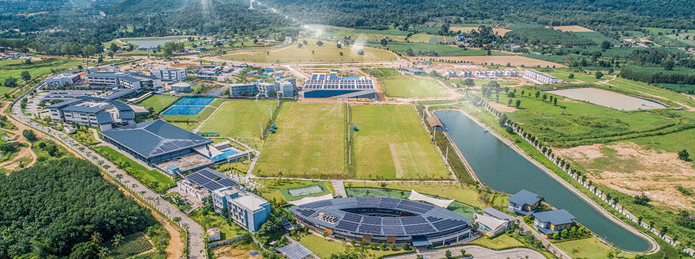 Modern international school campus with sports facilities and green spaces.