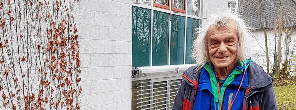 Colorful outdoor scene at a World Schools campus with an elderly man smiling.