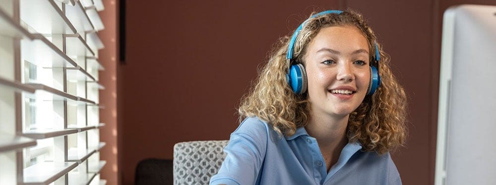 Engaging girl attending online class at a world school with headphones, learning remotely effectively.