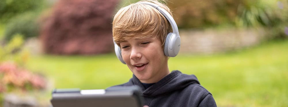 Kids studying on tablet with headphones outdoors for world-schooling education and global learning.