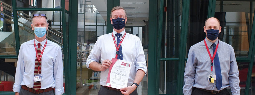 1. Teachers wearing masks in a modern school lobby promoting safe learning environments.