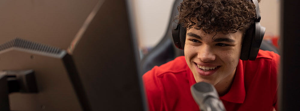Engaging student using computer with headphones at World Schools, emphasizing innovative education.