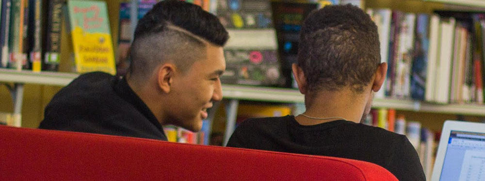 Modern students studying in a library, engaging with digital devices, exemplifying world-class education environments.