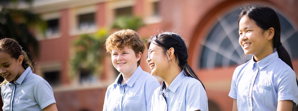 Modern diverse students smiling outdoors at a world school campus.