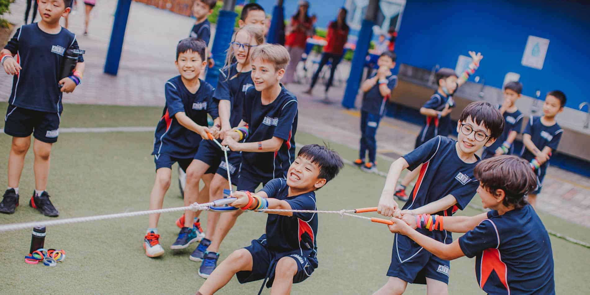 Playful children participating in tug-of-war game at school playground for active learning and development.