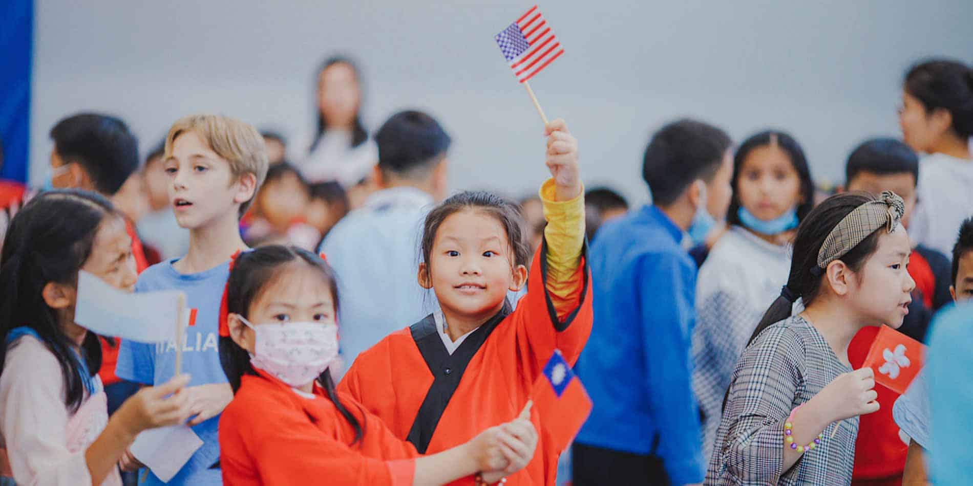 Cheerful multicultural children holding flags at an international school event, celebrating global unity and diversity.