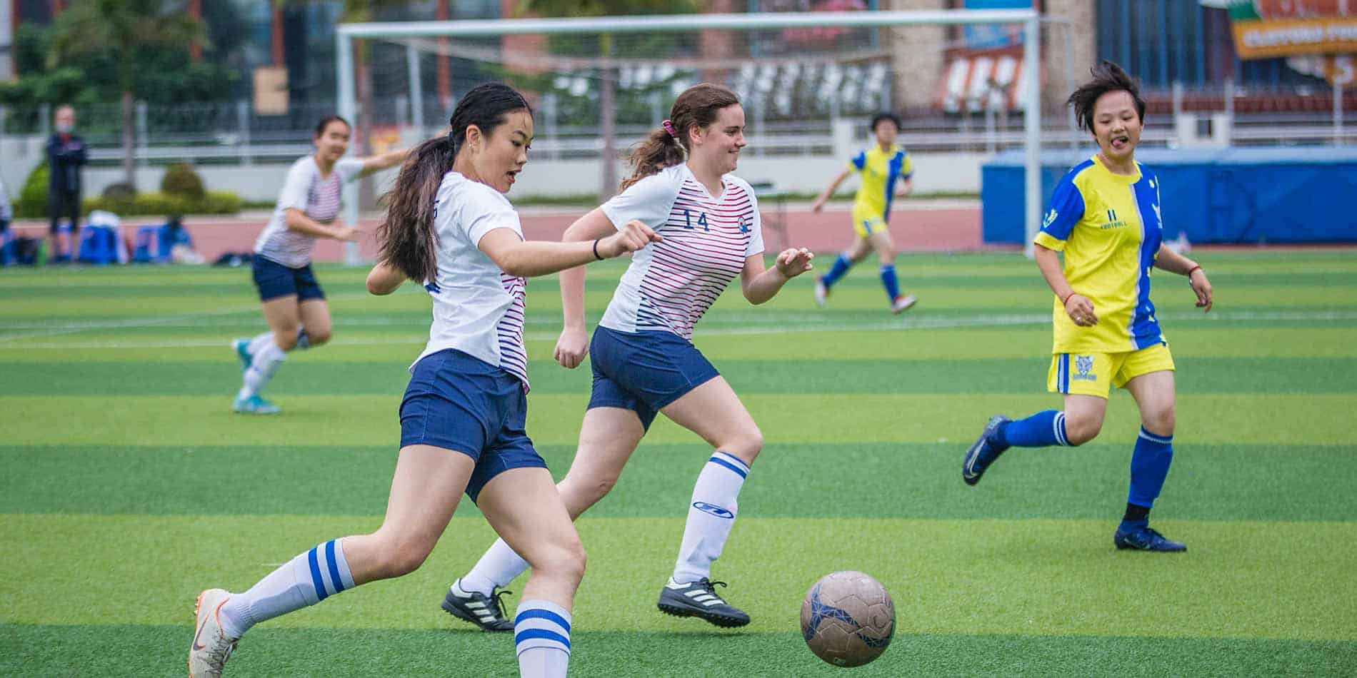 Bright diverse girls playing soccer on a sports field, school sports, teamwork, youth sports, healthy activity.