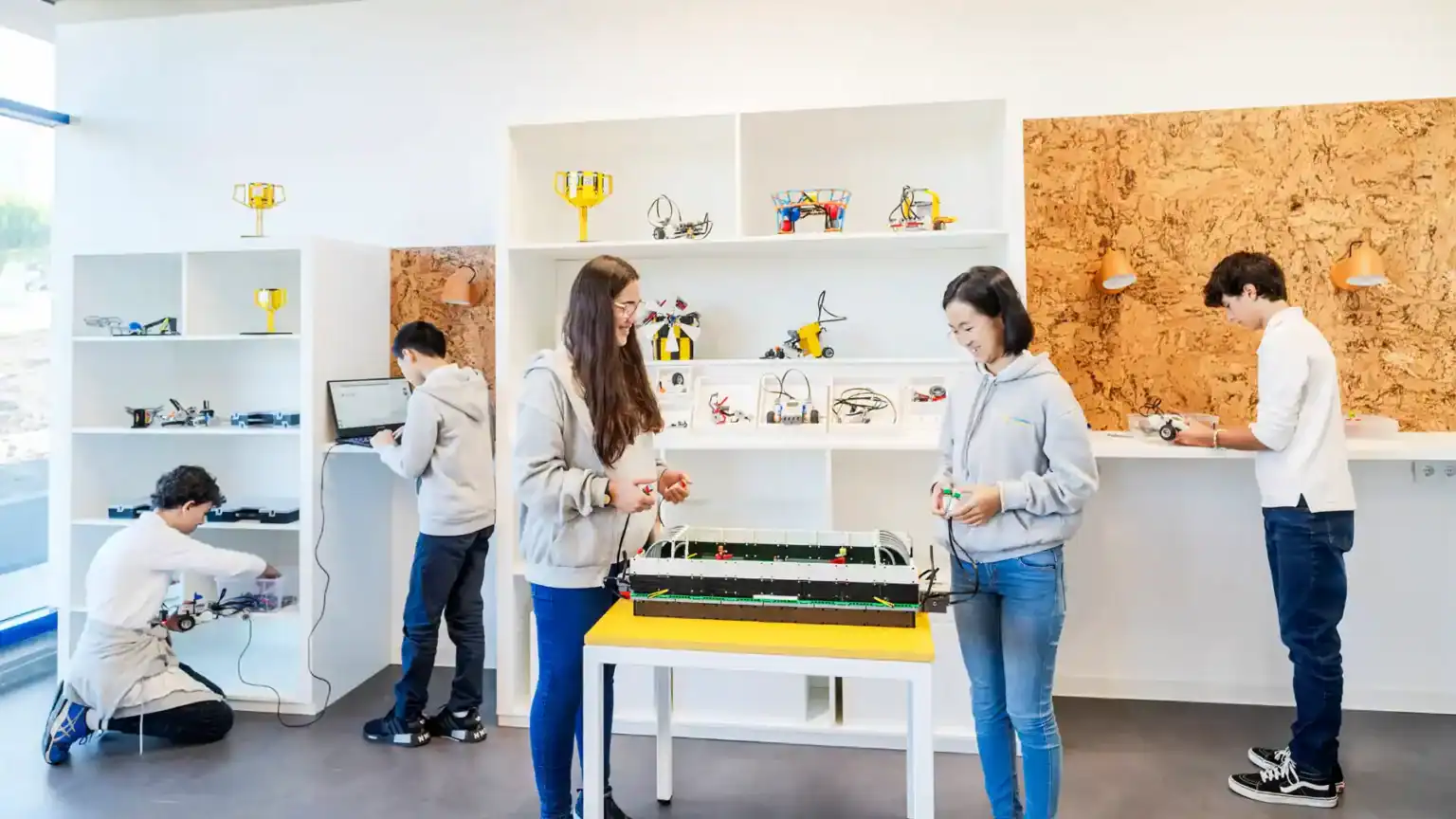 Robotics classroom with diverse students building and coding robots at an innovative World Schools program.