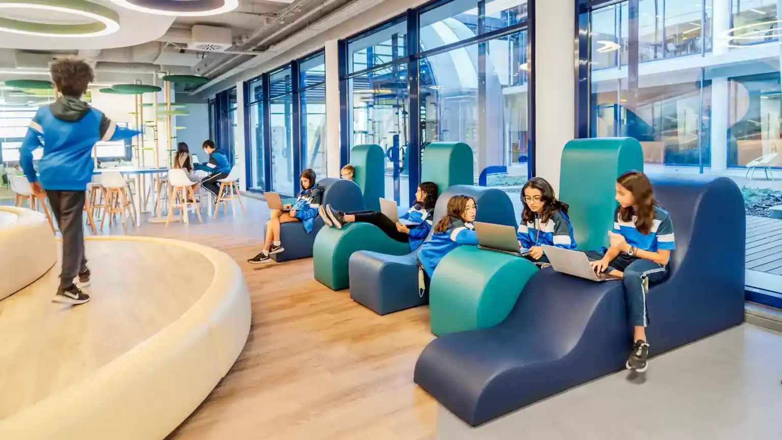 Bright modern school library with students using laptops and engaging in learning activities.
