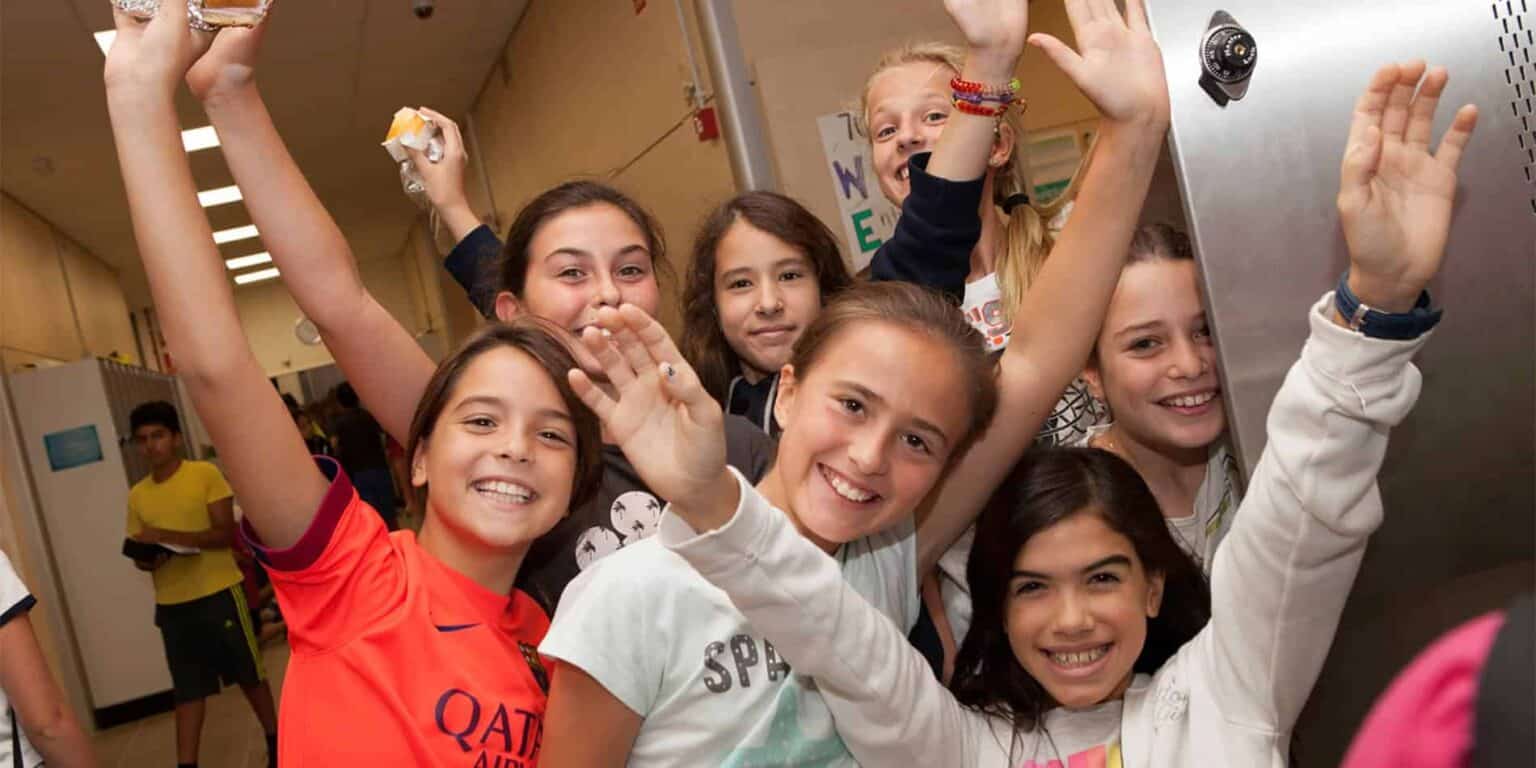 Vibrant group of diverse students smiling and celebrating in school hallway, showcasing joyful learning environment.