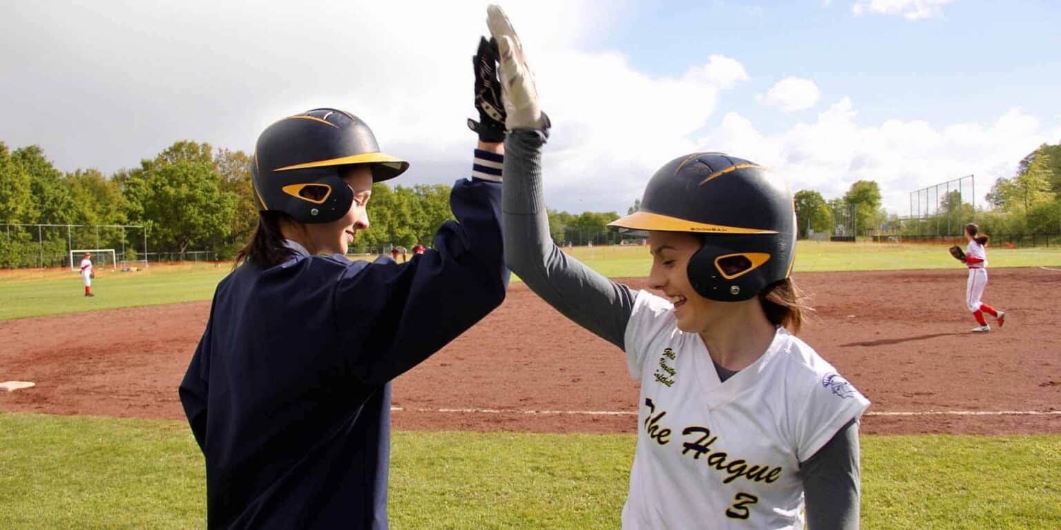 Girls celebrating a successful baseball game at an international school field, emphasizing sportsmanship and extracurricular activities.
