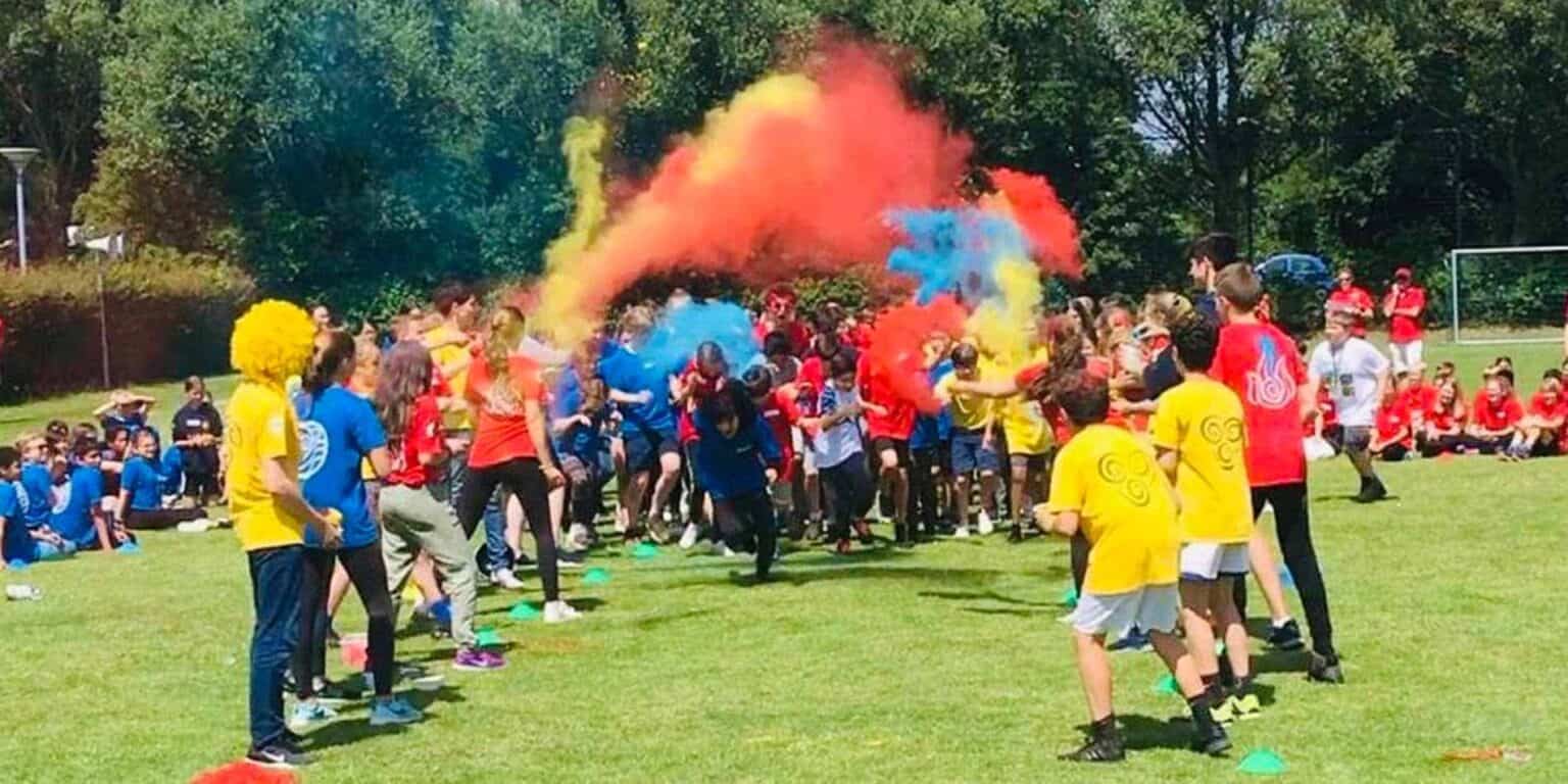 Colorful smoke bombs during outdoor school sports event, students enjoying team activities at modern school.