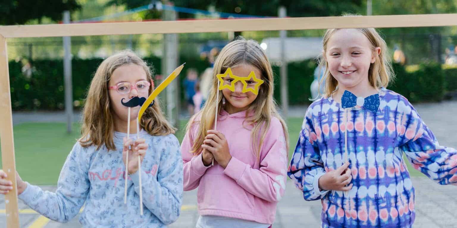 Children having fun at an international school playground with photo booth props.
