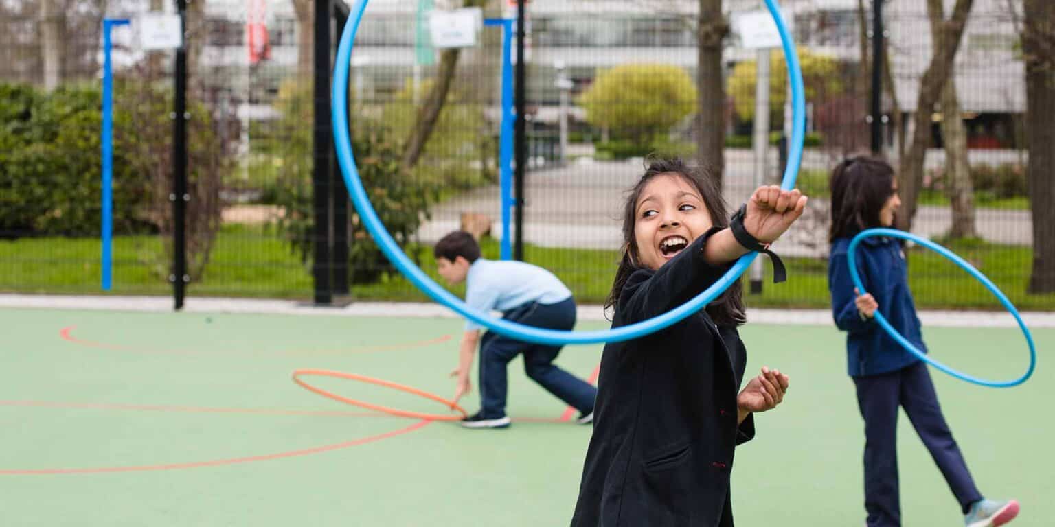 孩子们在国际学校运动场的户外玩呼啦圈。.
